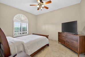 A bedroom with a bed, a television on a wooden dresser, a ceiling fan, and a window with blinds. - Tucson: Catalina Foothills Retreat (Tucson)