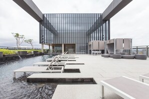 A modern building with a glass facade and a rooftop pool area with seating. - New Studio w/ Parking near República Metro DR1208 (República)