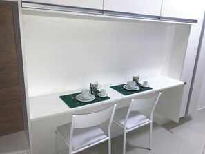 A white dining table with two chairs, a green placemat, and a set of white dishes and cups. - New Studio w/ Parking near República Metro DR1208 (República)