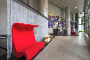 Un intérieur moderne avec un banc rouge, des œuvres d’art murales aux motifs géométriques et une cloison en verre.