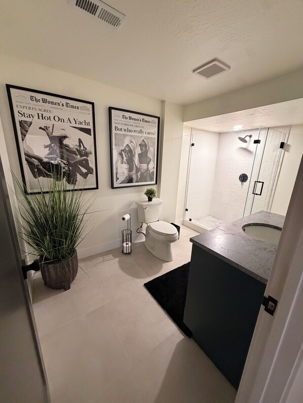 A modern bathroom with a toilet, bidet, and shower. There are two framed newspaper articles on the wall. - 4-bedroom House in Prime SLC Location Minutes From The U (Salt Lake City)