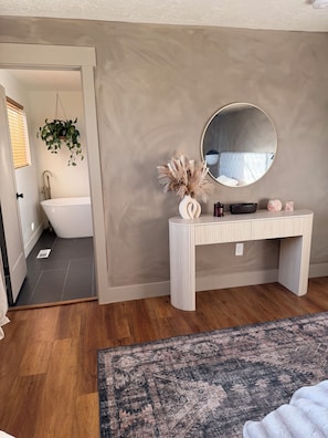 A bathroom with a bathtub, a vanity with a mirror, and a hanging plant. - 4-bedroom House in Prime SLC Location Minutes From The U (Salt Lake City)