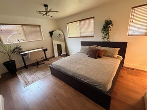 Ein Schlafzimmer mit Bett, Nachttischen, Schreibtisch, Spiegel und einer Topfpflanze.