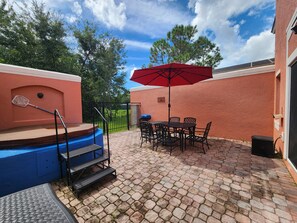 A patio area with a pool, outdoor seating, and a red umbrella. - Charming 3-bedroom townhome with AC in fantastic Kissimmee (Kissimmee)