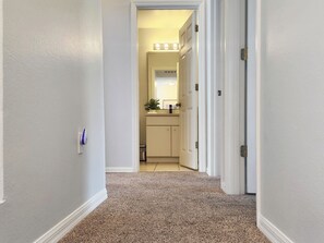 A hallway leading to a bathroom with a mirror, a sink, and a plant. - Charming 3-bedroom townhome with AC in fantastic Kissimmee (Kissimmee)