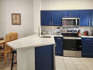 A kitchen with blue cabinets, a white countertop, a microwave, a stove, and a dishwasher. - Charming 3-bedroom townhome with AC in fantastic Kissimmee (Kissimmee)