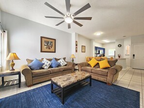 A living room with two sofas, a coffee table, and a ceiling fan. - Charming 3-bedroom townhome with AC in fantastic Kissimmee (Kissimmee)