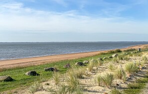 A coastal landscape with a sandy beach, grassy dunes, and a calm sea under a clear sky. - Gorgeous home in Esbjerg V with WiFi (Esbjerg V)