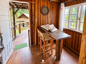A wooden interior with a dining area, a view of the outside, and a door leading to a covered outdoor space. - Sitio Estancia Rio Bonito - Blumenau/sc (Massaranduba)