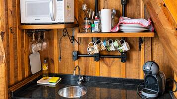 Una cocina compacta con microondas, cafetera y lavabo.