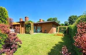 Ein Wohnhaus mit Backsteinfassade, einer Holzpergola, einem Rasen und einer Schaukel.