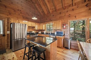 Een houten cabinestijl interieur met een keuken, inclusief een koelkast, fornuis, magnetron en barstoelen.