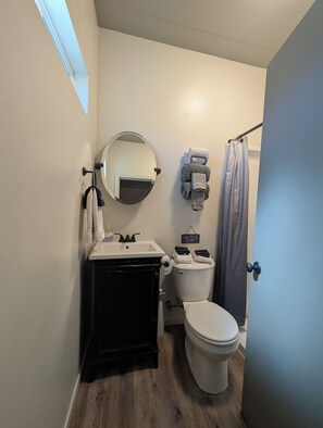 Een badkamer met een witte wastafel, een zwarte opbergkast, een wit toilet en een douchegordijn.