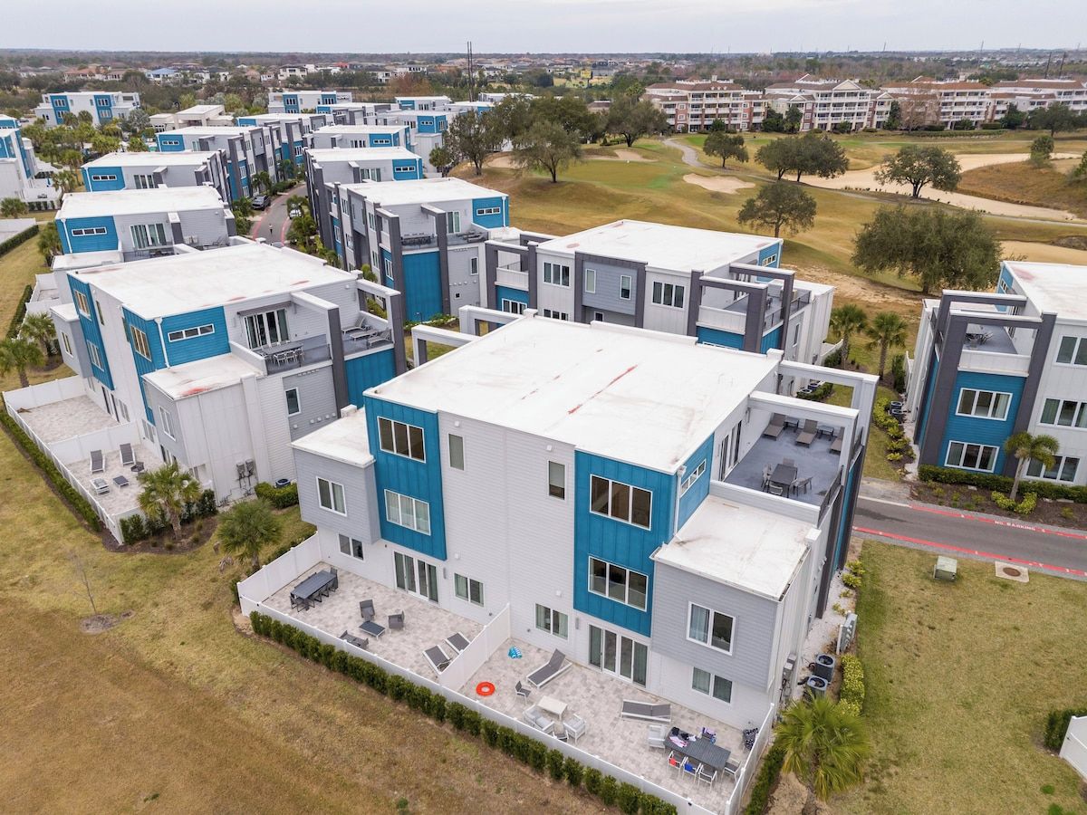 Un complexe résidentiel moderne composé de plusieurs bâtiments à deux étages, avec une cour centrale et un terrain de golf en arrière-plan.