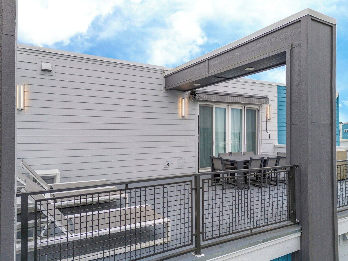 Un balcon avec une table et des chaises, une balustrade et un bâtiment doté d’une fenêtre et d’une porte.