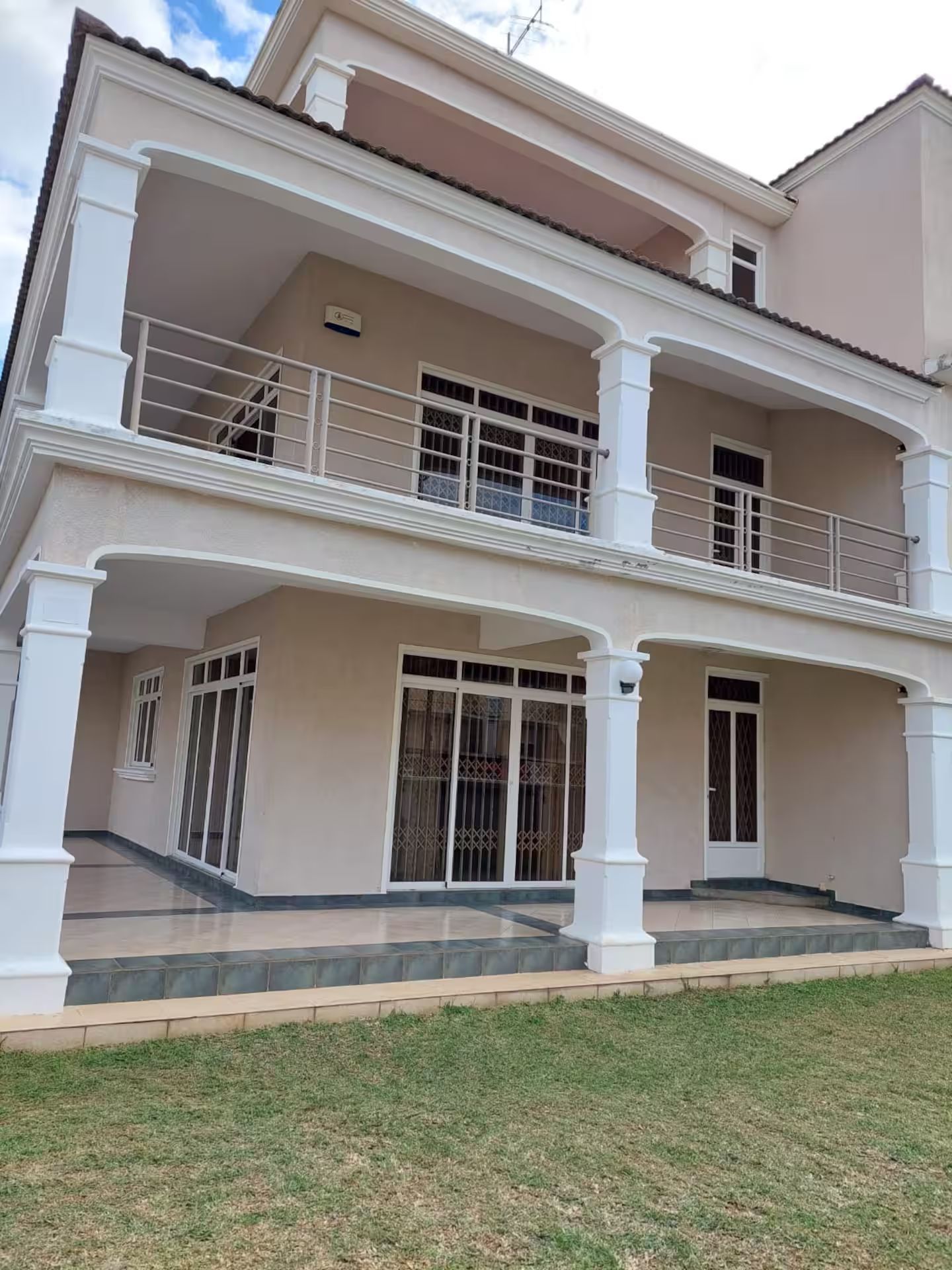A two-story building with a balcony on the upper floor, large windows, and a flat roof.