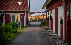 A pathway leading to a building with a red facade, a covered outdoor seating area, and a bicycle parked in front. - Awesome home in Varberg with swimming pool (Varberg)