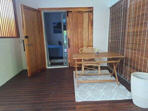 A small room with a wooden table and chairs, a white rug, and a wooden door leading to another room. - One Bedroom apartment with access to swimming pool (Beau Bassin-Rose Hill)