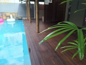 A wooden deck with a pool, a potted plant, and a white inflatable object. - One Bedroom apartment with access to swimming pool (Beau Bassin-Rose Hill)