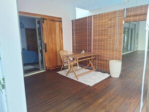 A room with a wooden floor, a table with chairs, a sliding door, and a bamboo screen. - One Bedroom apartment with access to swimming pool (Beau Bassin-Rose Hill)