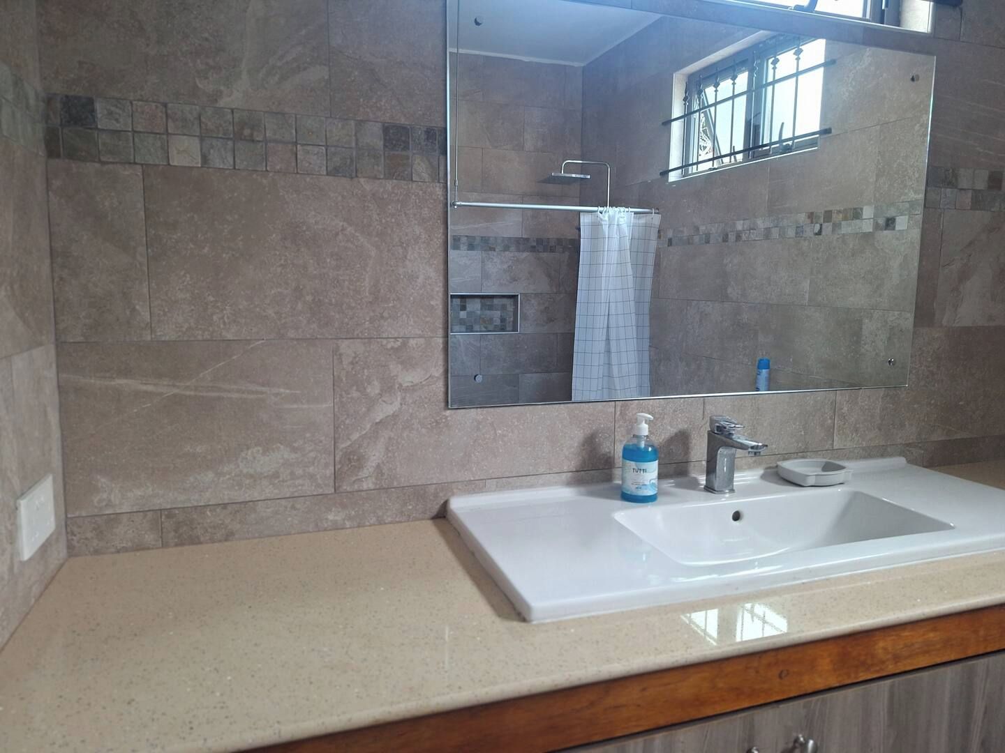 Une salle de bain avec un grand miroir, un lavabo et un espace douche.