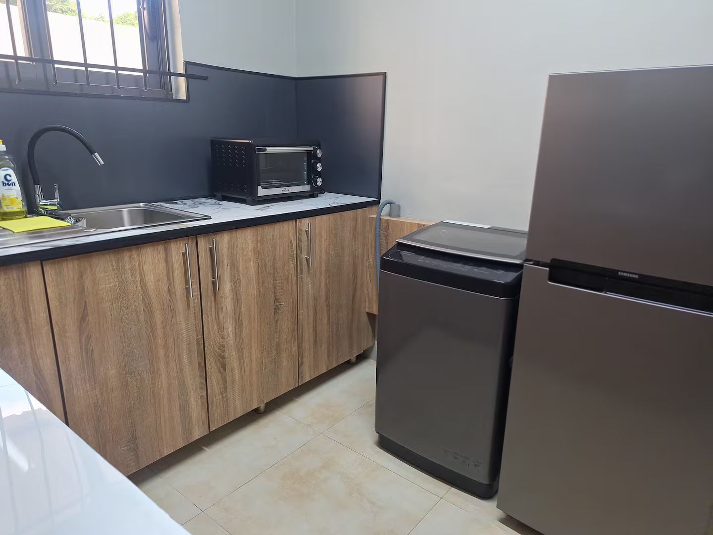 A compact kitchen with a microwave, a refrigerator, wooden cabinets, and a sink.