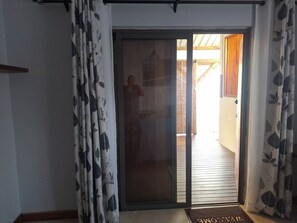 A sliding glass door leading to a wooden deck area. - One Bedroom apartment with access to swimming pool (Beau Bassin-Rose Hill)
