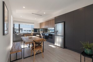 A modern kitchen with a dining area, large windows, and a view of the city. - Maison Central | 3BR 3 Bath + Parking | CBD Luxe (Adelaide)