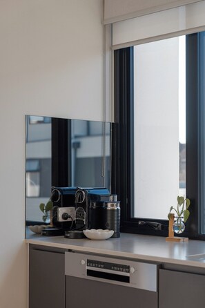 Eine moderne Küche mit integrierter Espressomaschine, Kaffeemühle und einer kleinen Pflanze auf der Arbeitsfläche.