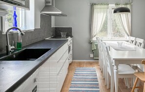 Eine moderne Küche mit schwarzem Arbeitsplatz, weißen Schränken, einem eingebauten Backofen und einem Fenster mit transparenten Vorhängen.