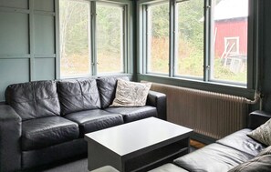 Ein modernes Wohnzimmer mit einer Ledersofa, einem weißen Couchtisch und Blick durch große Fenster.