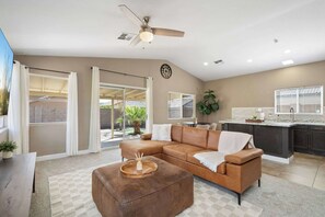 A spacious living room with a brown leather sofa, a coffee table, and a ceiling fan. - 3BR Phoenix Retreat Near Golf & Water Parks (Phoenix)
