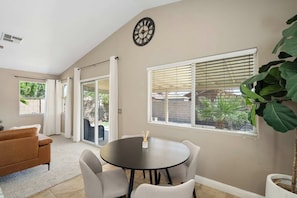 A room with a round table and chairs, a sofa, a large window with blinds, and a wall clock. - 3BR Phoenix Retreat Near Golf & Water Parks (Phoenix)