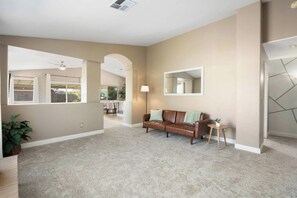 A spacious living area with a brown leather sofa, a small side table, and a floor lamp. - 3BR Phoenix Retreat Near Golf & Water Parks (Phoenix)