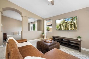 A living room with a large flat-screen TV, a brown leather sofa, a wooden coffee table, and a dark wooden entertainment unit. - 3BR Phoenix Retreat Near Golf & Water Parks (Phoenix)