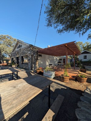 A rustic outdoor seating area with stone walls, wooden tables, and planters. - Clingan's Junction Cottage at Clingan's Junction Cabins & Coffee (Yokuts Valley)