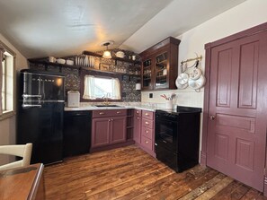 Une cuisine équipée d’un réfrigérateur, d’une cuisinière, d’un évier et dotée d’un plancher en bois.