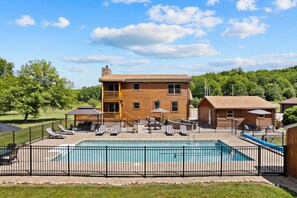 Eine Holzhütte mit Pool, umzäunt und mit blauem Himmel.