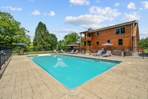 A rectangular swimming pool with a clear blue surface, surrounded by a paved deck. - Cozy Wooded Cabin Retreat | Fireplace, Fire Pit, Jetted Tub | Sleeps 8 (Harrisville)