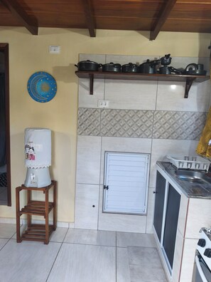 Cocina compacta con dispensador de agua, estufa y lavaplatos.