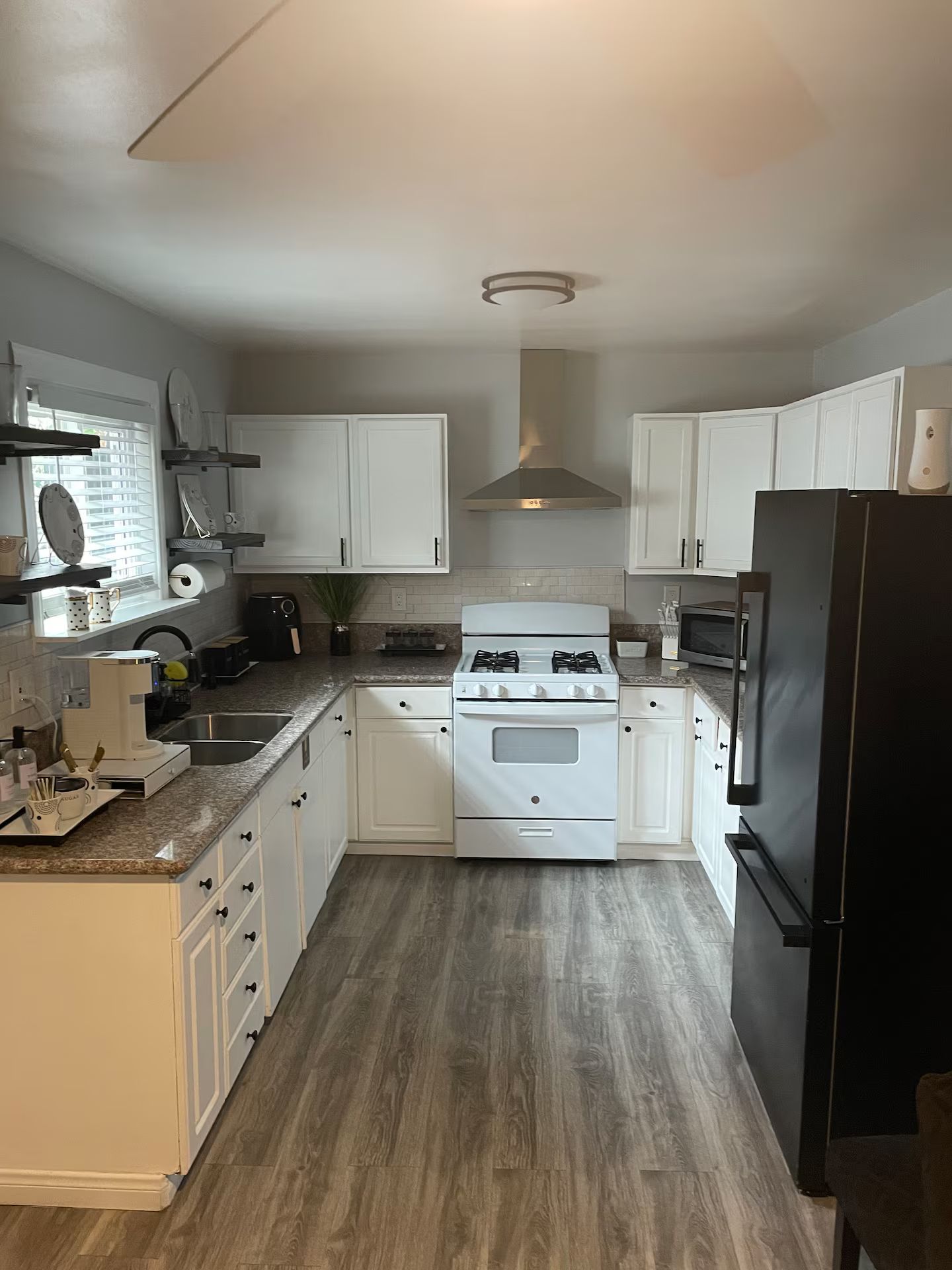 A kitchen with white cabinets, a stove, a microwave, and a refrigerator.
