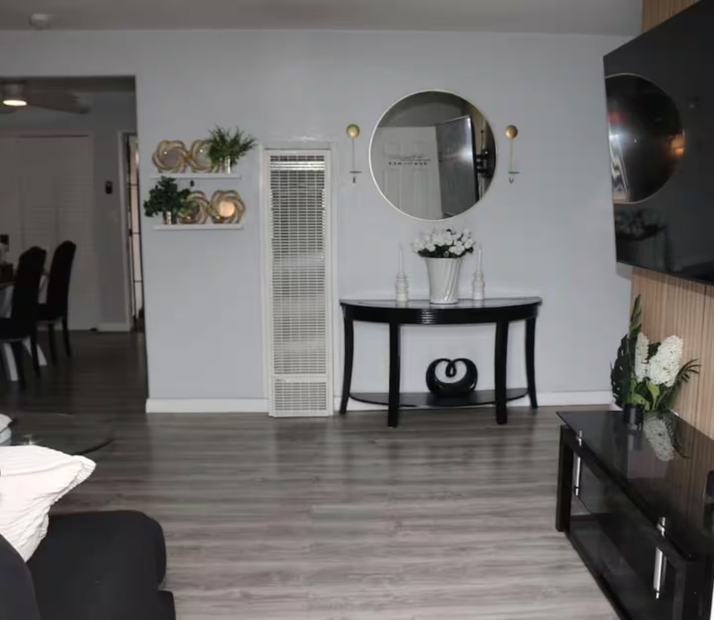 A modern living room with a dining area, a large mirror, and a flat-screen TV.