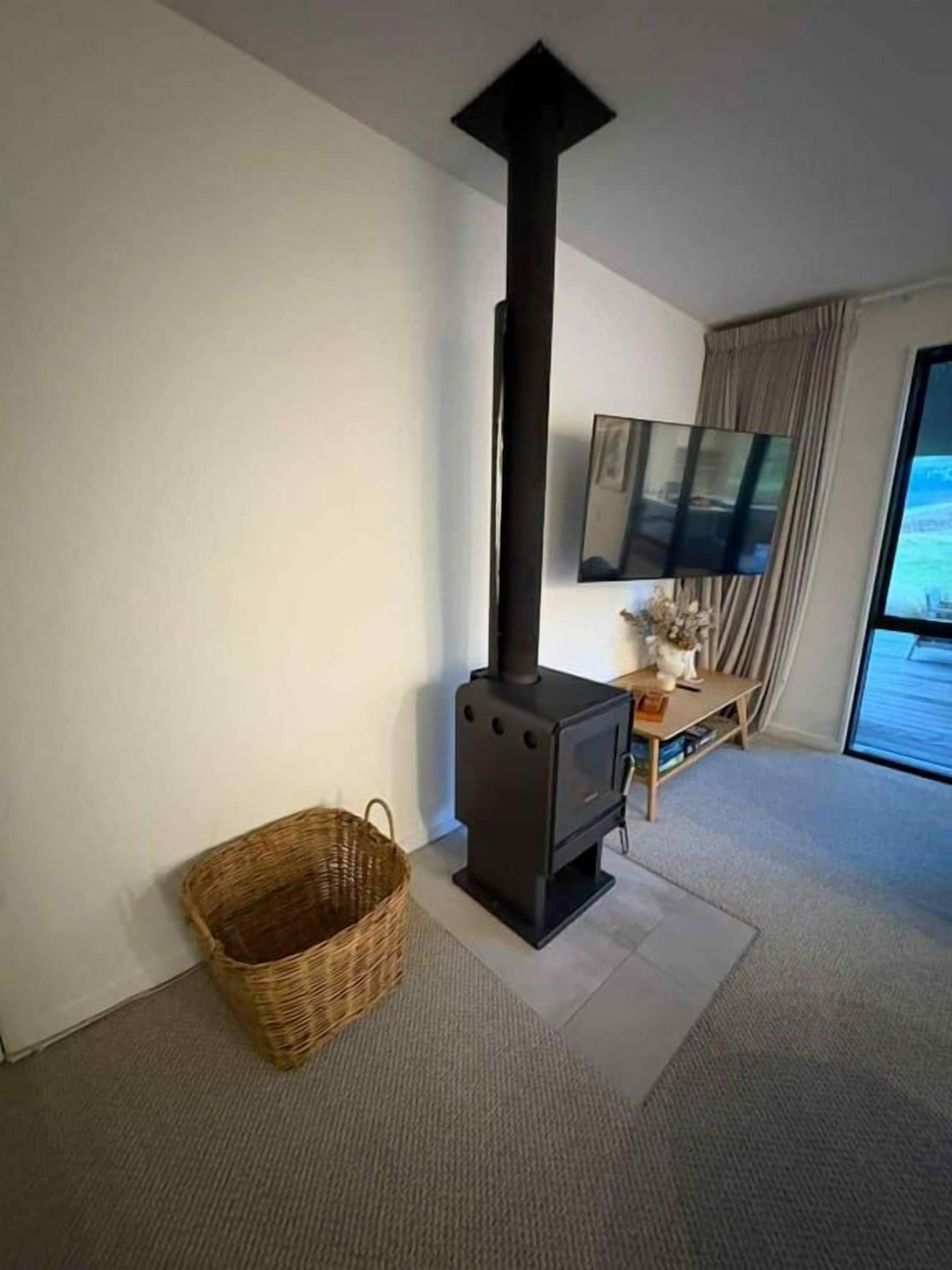 A room with a fireplace, a television mounted on the wall, and a window with curtains.