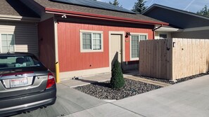 Un edificio residencial con fachada roja, cerca de madera y un automóvil estacionado frente a él.