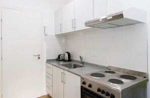Een kleine keuken met witte kasten, een roestvrijstalen fornuis en een ingebouwde oven.