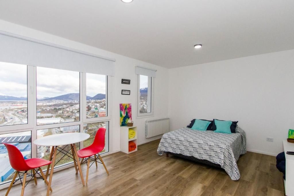 Une chambre avec un lit, une fenêtre donnant sur la ville, une petite table et deux chaises.