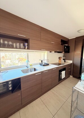 Eine moderne Küche mit Holzschränken, einer Edelstahl-Spüle und einer eingebauten Mikrowelle.