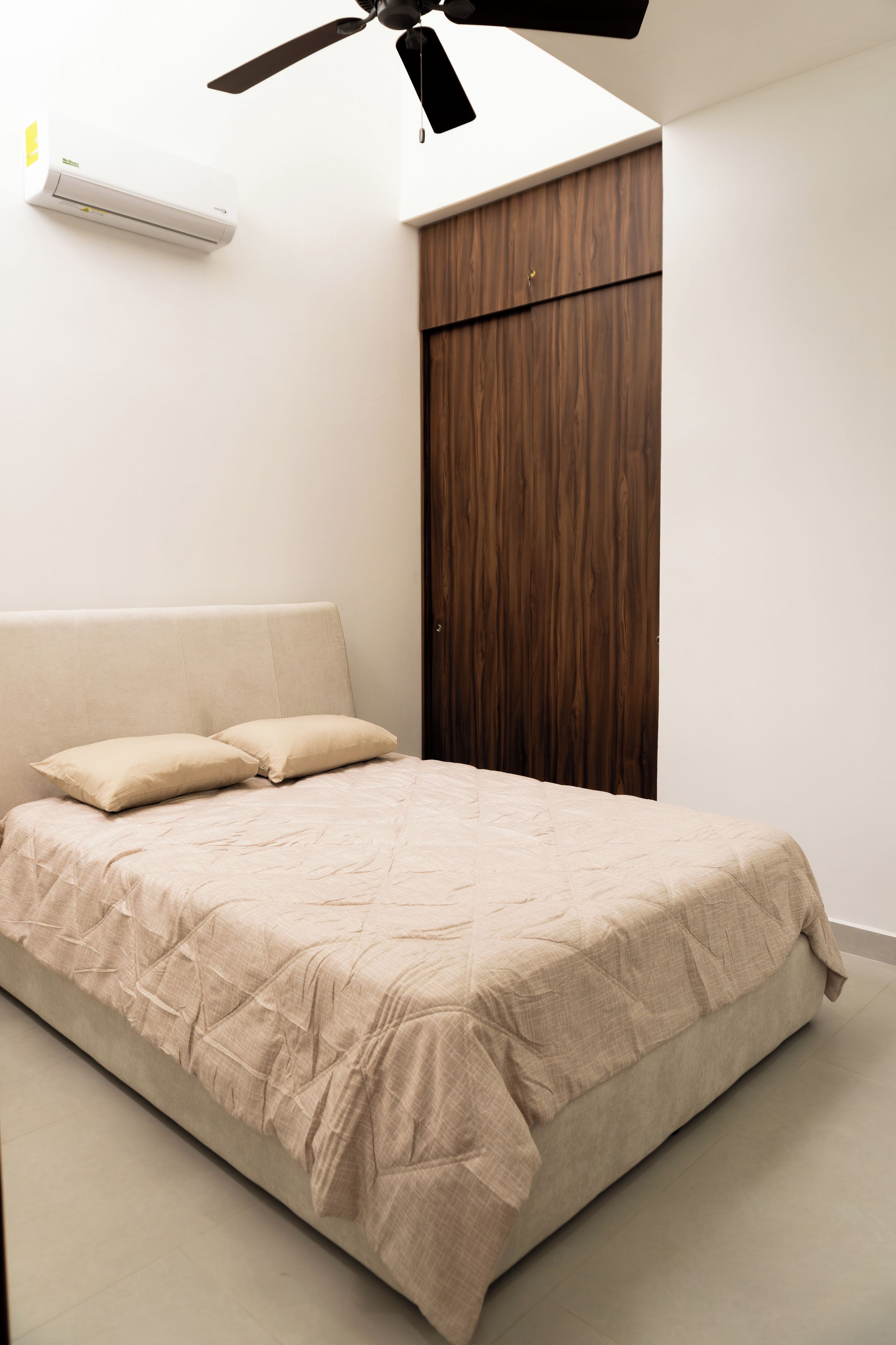 Un dormitorio con una cama, ventilador de techo y armario.