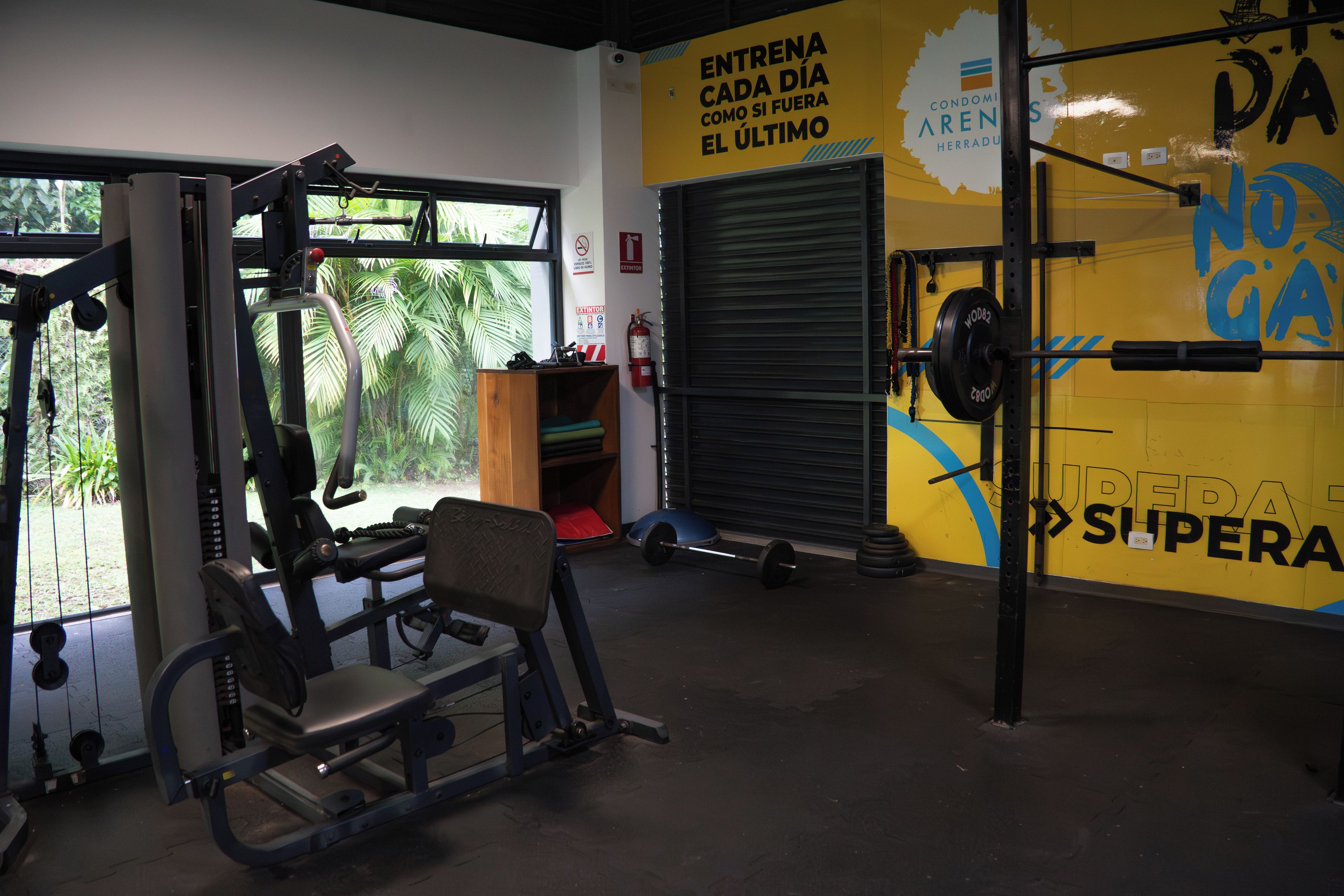 A gym with exercise equipment, a weight bench, and a wall with motivational text.