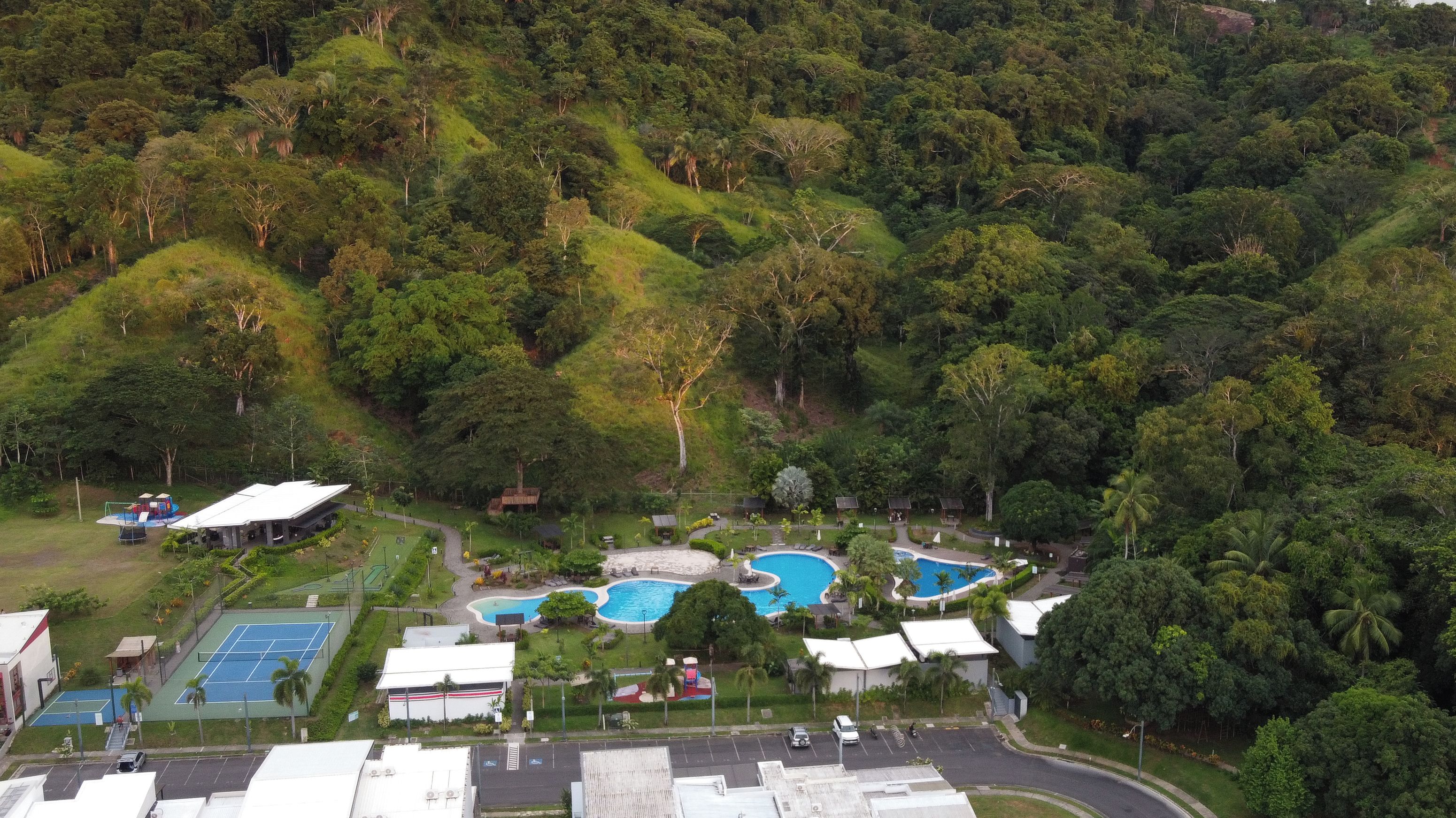 A resort with multiple swimming pools, tennis courts, and a lush green landscape.